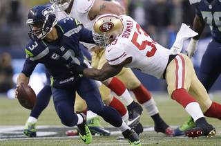 Seattle Seahawks' Russell Wilson is sacked by San Francisco 49ers' NaVorro Bowman (53) during the first half of the NFL football NFC Championship game Sunday, Jan. 19, 2014, in Seattle. (AP Photo/Marcio Jose Sanchez)
